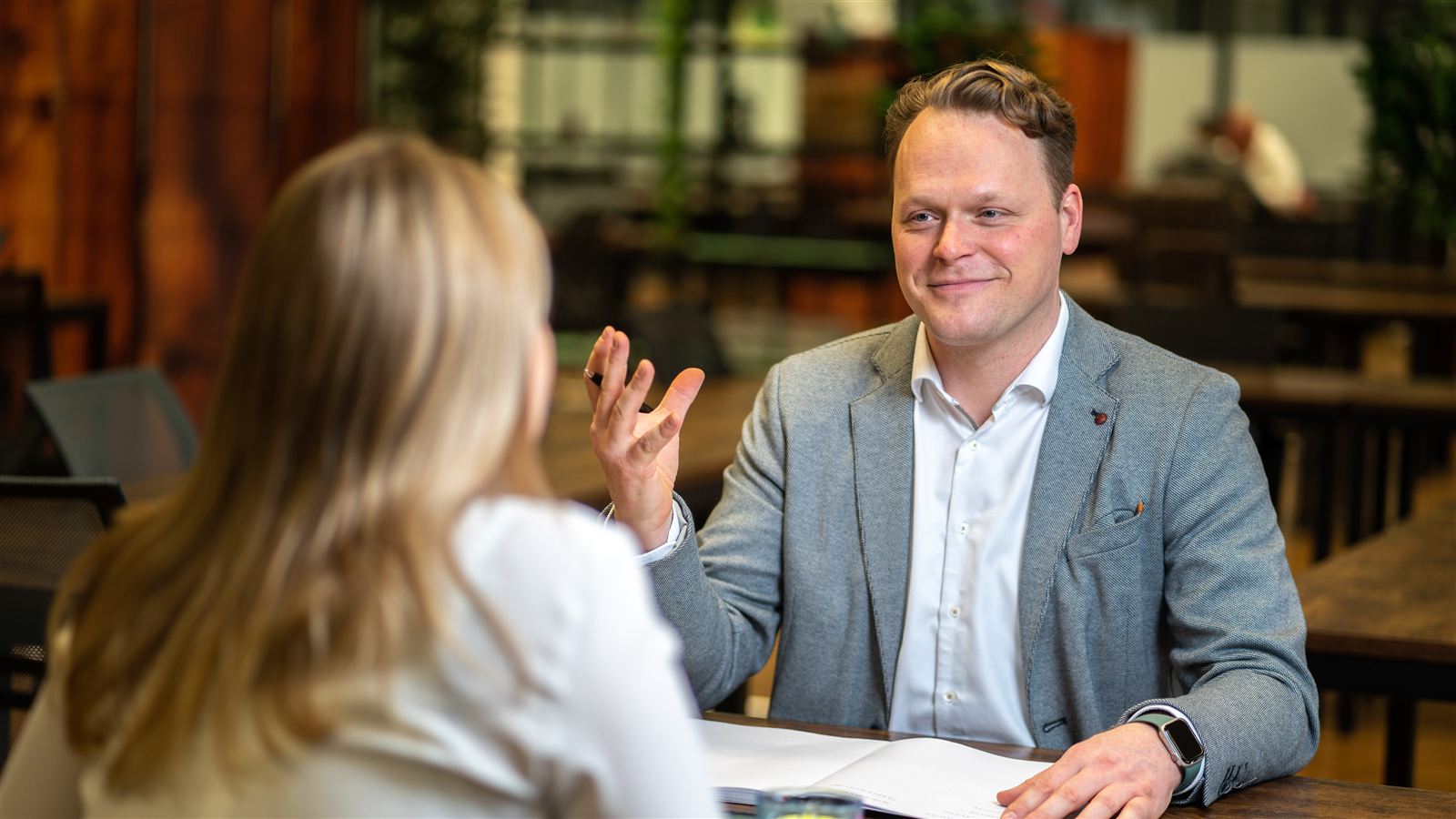 John Alexander Bräuß im Beratungsgespräch (Szene und Hintergrund KI-bearbeitet)